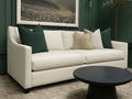 Lease sofa in Calgary with green and beige cushions in a room with a dark green wall and a framed picture.