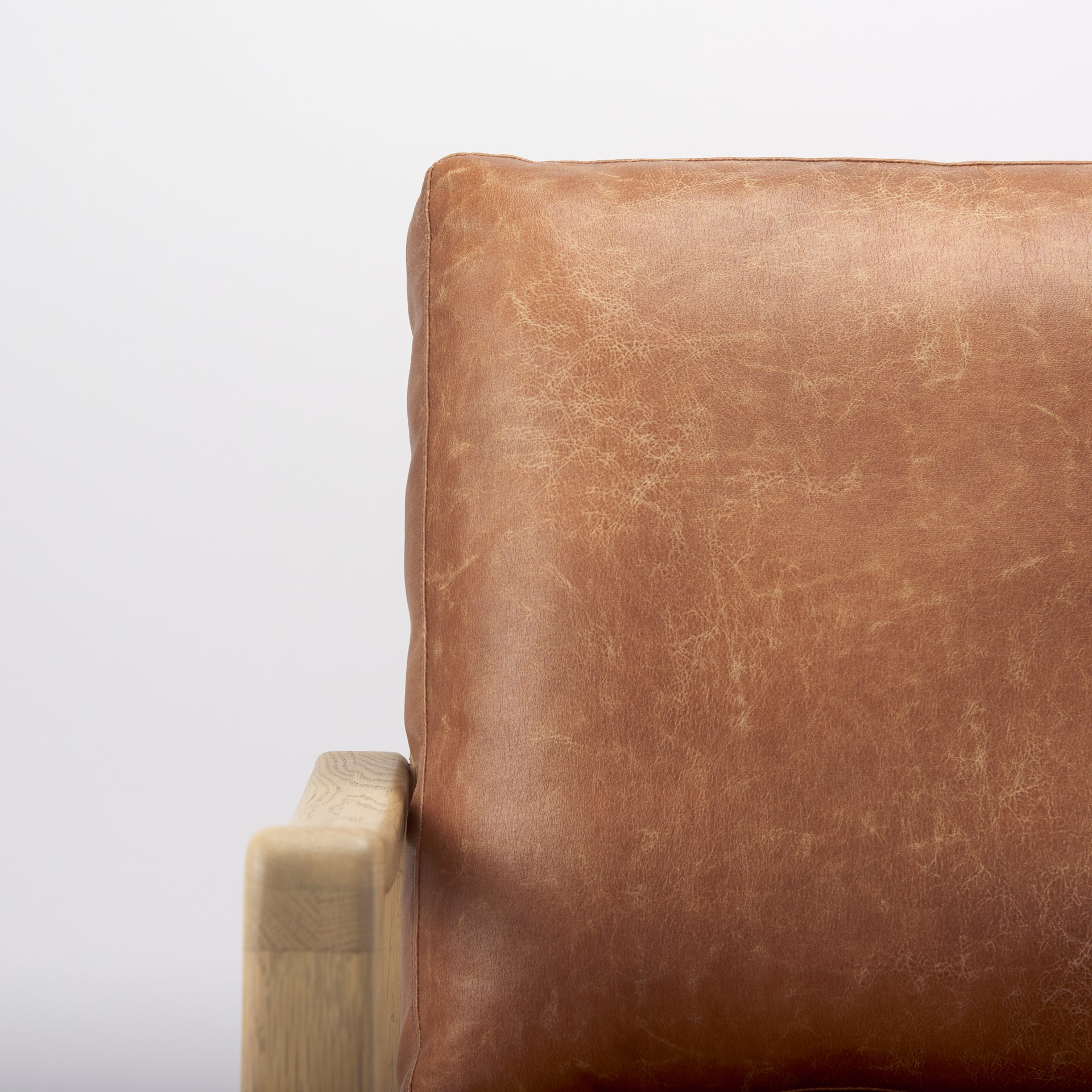 Close-up of Raeleigh Tan Faux Leather Accent Chair in Calgary with wooden frame