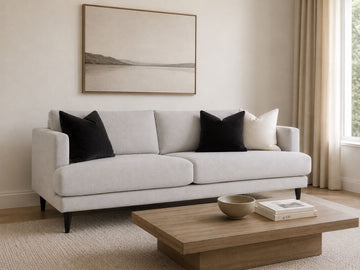 Light fabric sofa with black accent pillows in a modern living room.