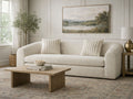 Curved light fabric sofa with wood coffee table in a neutral living room.