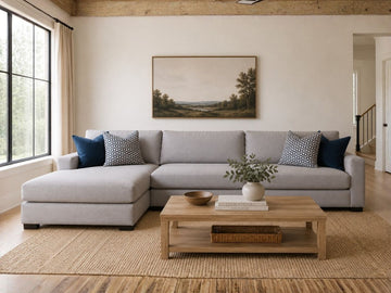 Light gray fabric sectional with chaise and blue accent pillows in a cozy modern living room.
