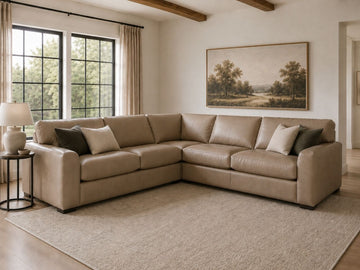 Tan leather sectional sofa with accent pillows in a bright, modern living room.