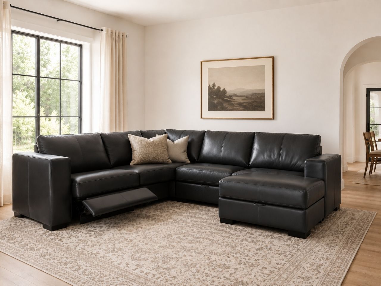 Black leather sectional with reclining seats in a bright modern living room.