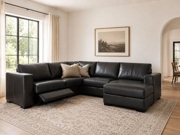 Black leather sectional with reclining seats in a bright modern living room.