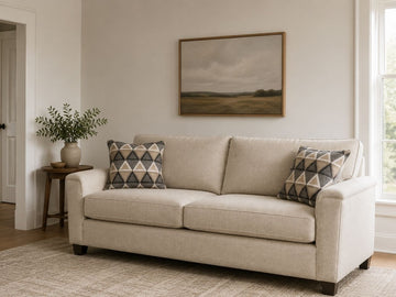 Light beige sofa with geometric accent pillows in a cozy, modern living room.
