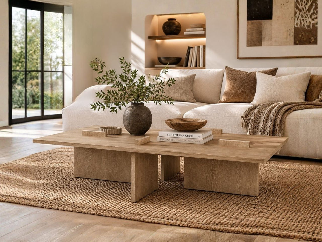 Light oak rectangular coffee table with architectural pedestal legs, styled in a bright and inviting living room.