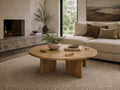 Round wood coffee table with a low-profile design in a modern living room.