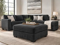 Charcoal grey upholstered ottoman with matching sectional sofa in a modern living room, featuring stylish ottoman furniture in Calgary and contemporary home décor.