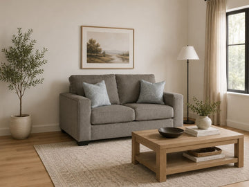 Light gray loveseat with soft accent pillows in a cozy neutral-toned living room.