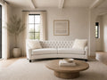 Curved cream tufted sofa with accent pillows in a bright, elegant living room.