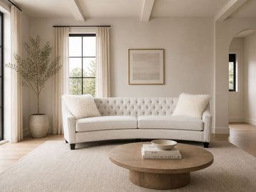 Curved cream tufted sofa with accent pillows in a bright, elegant living room.