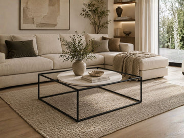 Modern square coffee table with a marble top and minimalist black metal frame, styled in a contemporary living room.