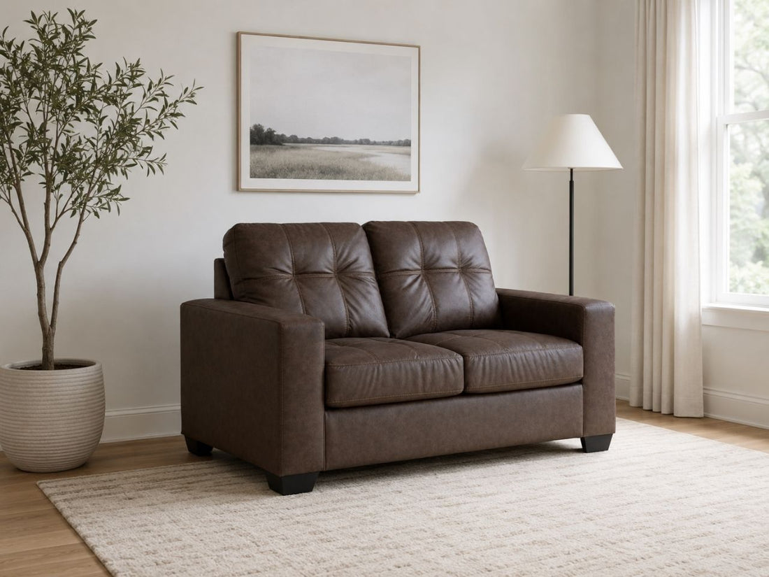 Dark brown faux leather loveseat with tufted cushions in a clean and modern living room.