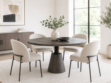 Round dark wood dining table with four cream upholstered chairs in a bright modern dining room.