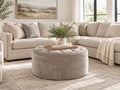 Round grey tufted ottoman styled with a cream sectional in a bright modern living room, perfect for ottoman furniture in Calgary and cozy contemporary home décor.