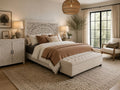 White carved wood king bed in a bright, modern bedroom with neutral bedding and a tufted bench.