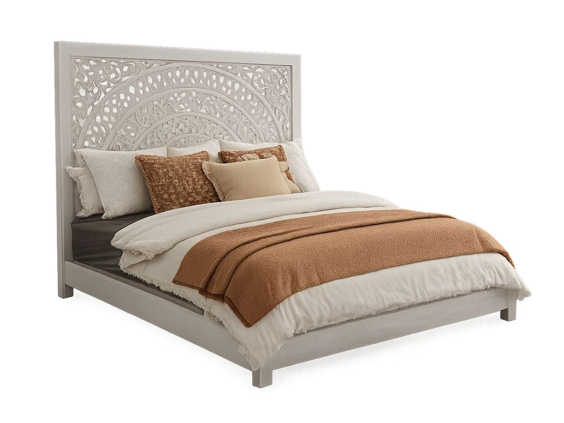 White carved wood king bed in a bright, modern bedroom with neutral bedding and a tufted bench.