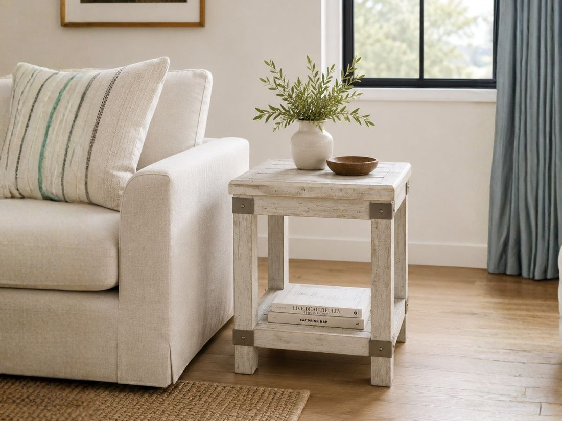 Rustic whitewashed wood end table with an open lower shelf, styled beside a cream sofa in a cozy farmhouse-inspired living room.