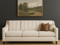 Custom Chanel sofa with brown pillows against a dark wall with a landscape painting.