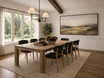 Solid wood dining table with six chairs in a bright dining room.