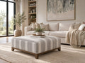 Light grey striped upholstered ottoman with a warm wood base, styled in a modern neutral living room — a versatile ottoman in Calgary for contemporary home décor.