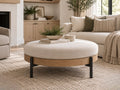 Round cream upholstered ottoman with a natural wood frame and black metal legs.