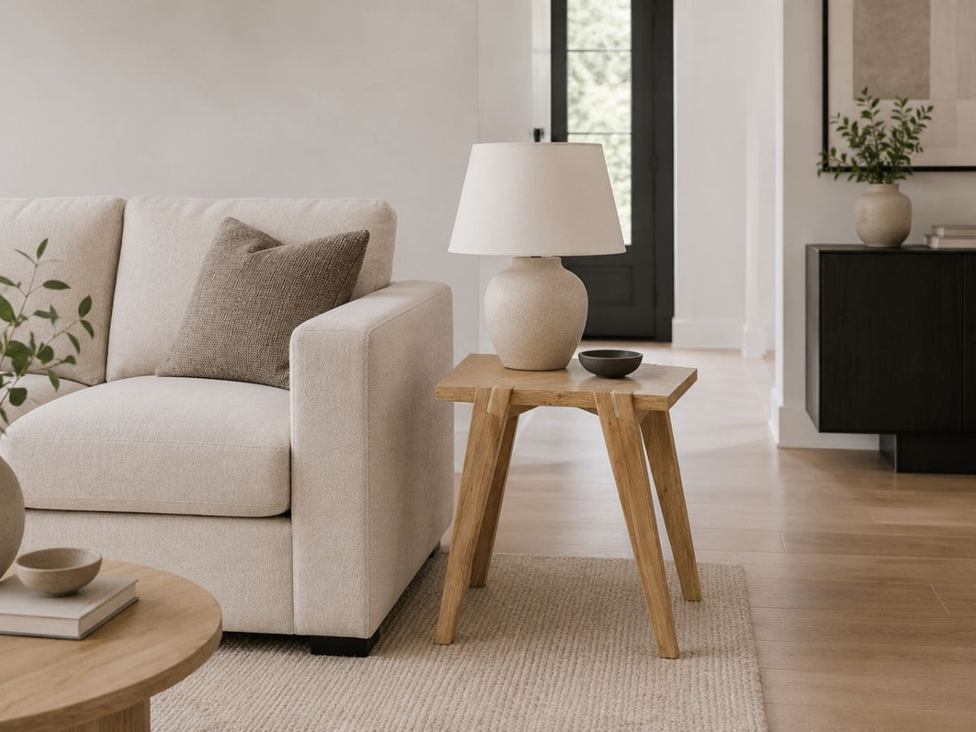 Light wood side table beside a cream sofa in a bright modern living room.