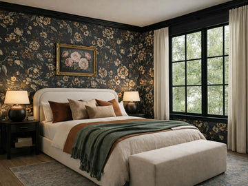 Upholstered bed with a soft curved headboard, styled in a cozy bedroom with floral wallpaper and dark-framed windows.