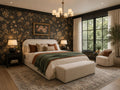 Cozy upholstered bed in a moody bedroom with dark floral wallpaper, warm lighting, and neutral accent decor.