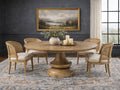 A round wood dining table with woven chairs in a moody, elegant dining room.