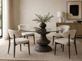 Round glass-top dining table with a sculptural black pedestal base and four upholstered dining chairs.