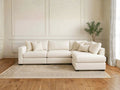 A bright white L-shaped fabric sectional in a minimalist room with white wall molding.