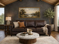 A three-cushion deep leather sofa is set against a dark charcoal-gray accent wall under a vaulted wood-plank ceiling.