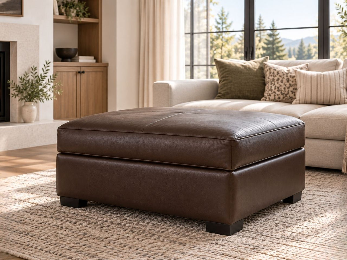 Brown leather ottoman in a warm, modern living room with neutral décor and natural light.