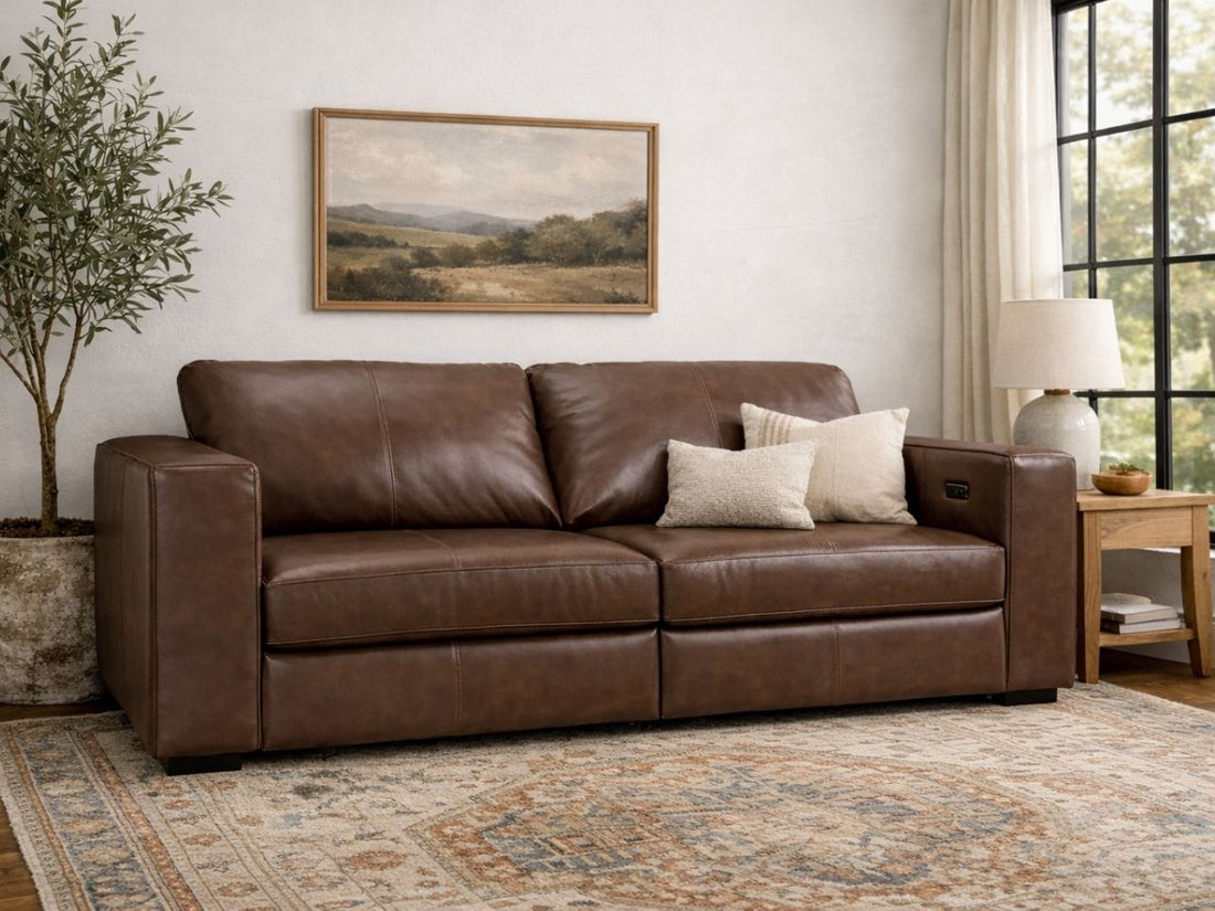 A dark brown leather sofa with plush cushions in a warm, neutral living room.