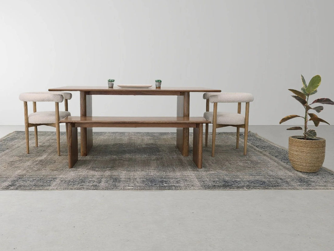 Rectangular wooden dining table with pedestal legs and six upholstered chairs in a bright, modern dining room.