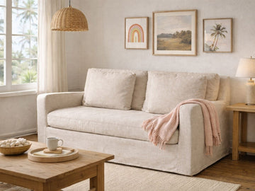Beige upholstered loveseat styled in a cozy living room with wood accents and wall art.