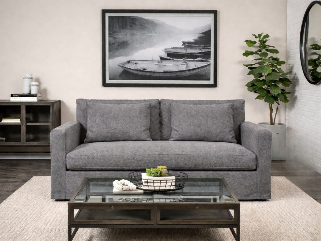Flint gray upholstered loveseat styled in a modern living room with a glass coffee table and framed wall art.