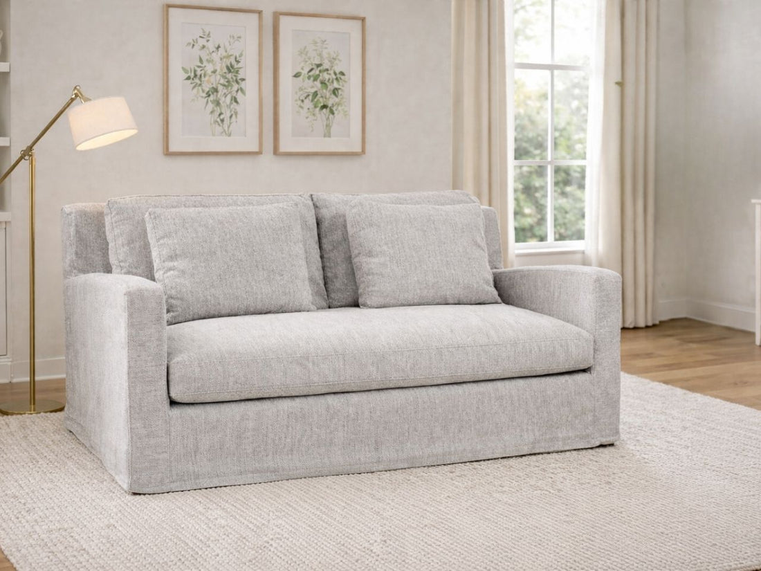 Frost gray upholstered loveseat styled in a bright living room with a floor lamp and framed wall art.