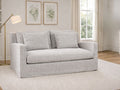 Frost gray upholstered loveseat styled in a bright living room with a floor lamp and framed wall art.