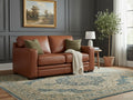 Warm brown loveseat upholstered in genuine or faux leather, styled in a cozy, traditional living room.