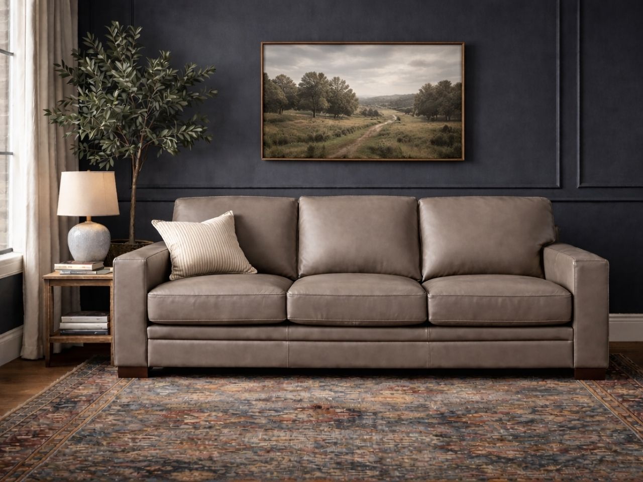 Three-seat sofa upholstered in leather or leather-like material, placed in a modern, neutral living room.
