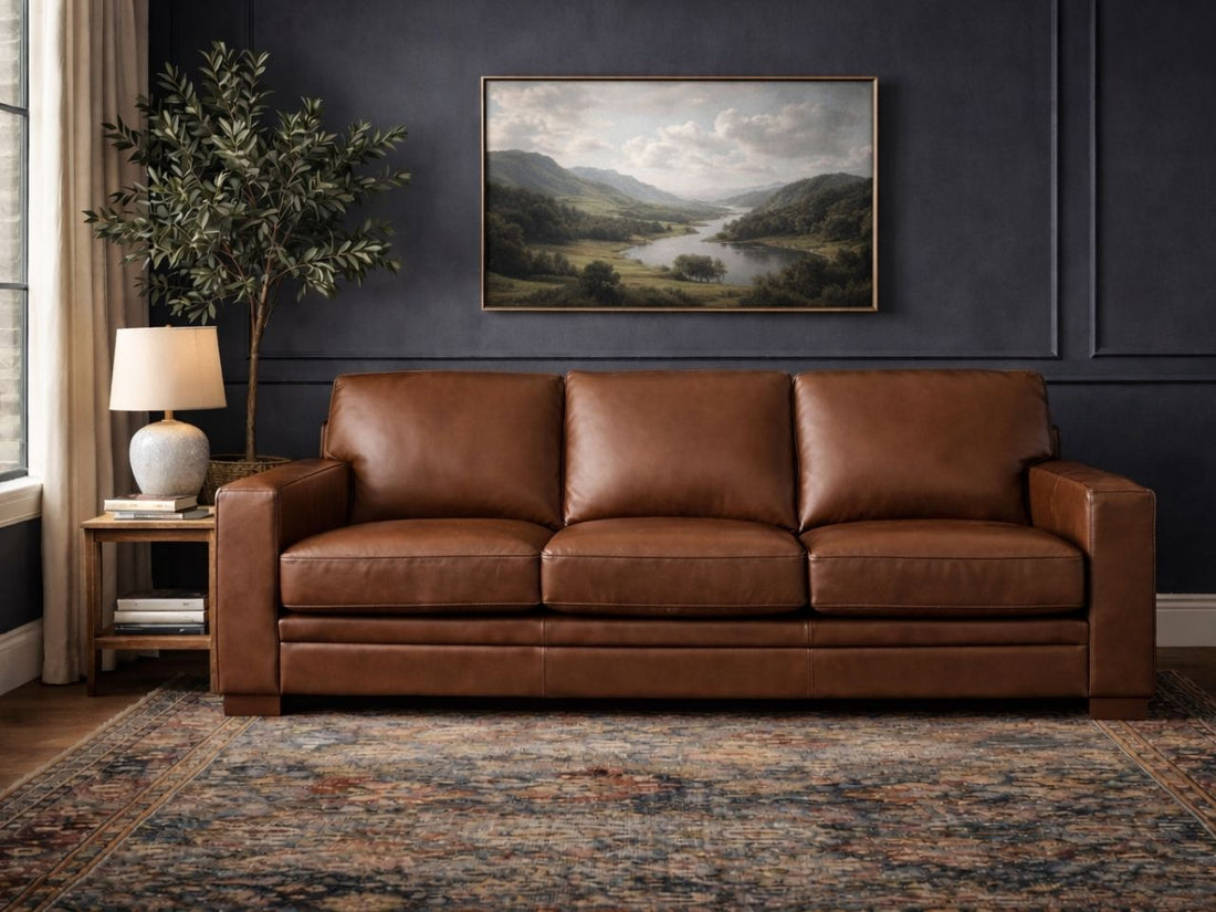 Cream three-seat sofa upholstered in smooth leather or leather-look fabric, styled in an elegant living room with dark walls.