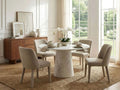 Round marble dining table with upholstered chairs in a bright, elegant dining room.