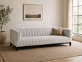 Light channel-tufted sofa with accent pillow in a modern, neutral living room.