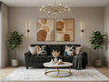 Dark gray sofa in a modern living room with abstract wall art, a round coffee table, and indoor plants.