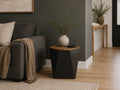 Black geometric accent table with a natural wood top styled beside a charcoal sofa in a contemporary living room.