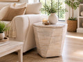 Light brown geometric wood side table with a faceted design, styled beside a cream sofa in a bright modern living room.