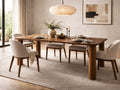 Solid wood rectangular dining table with upholstered chairs in a neutral dining room.