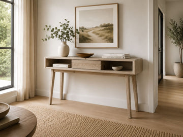 Light wood console table with open storage styled in a bright modern entryway.